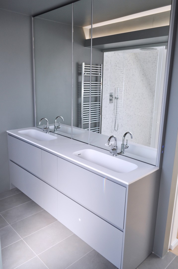 Bagno realizzato su misura. Sportelli in finitura laccata, top in corian, specchi retroilluminati da LED. Cassetti interni in rovere massiccio con finitura naturale Biologica.
