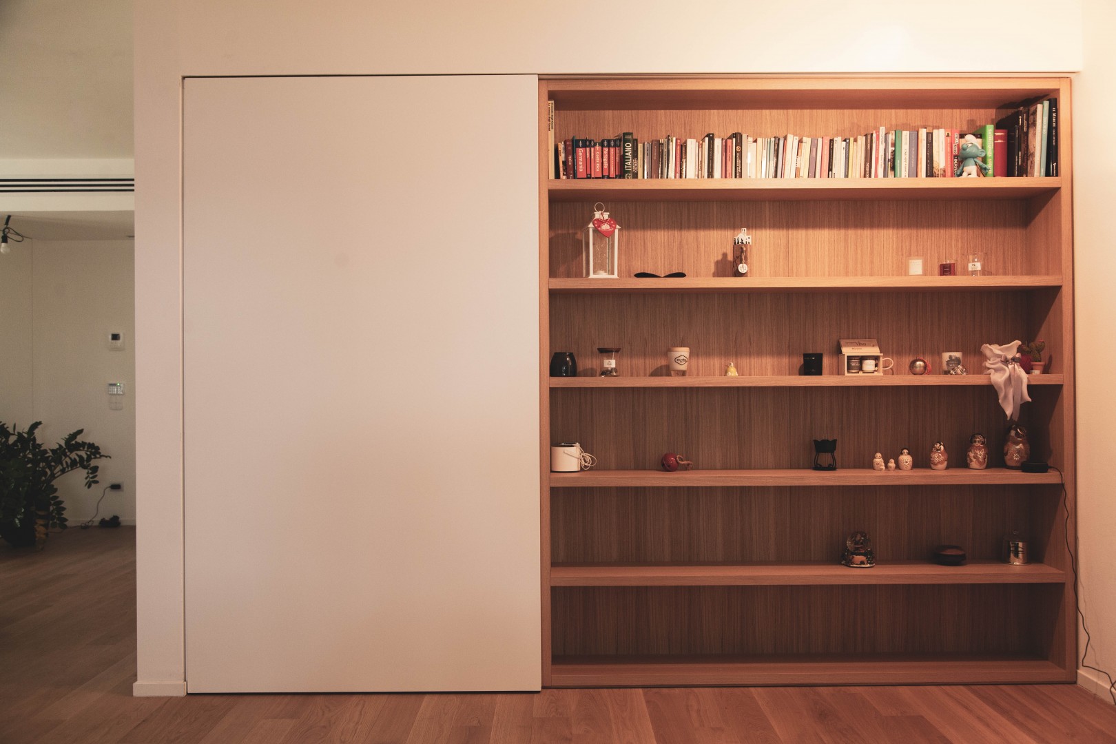 Arredamento su misura realizzato da Profili - Falegnameria & Design. Libreria e zona ufficio con scrivania realizzati in legno rovere. con anta scorrevole laccata.