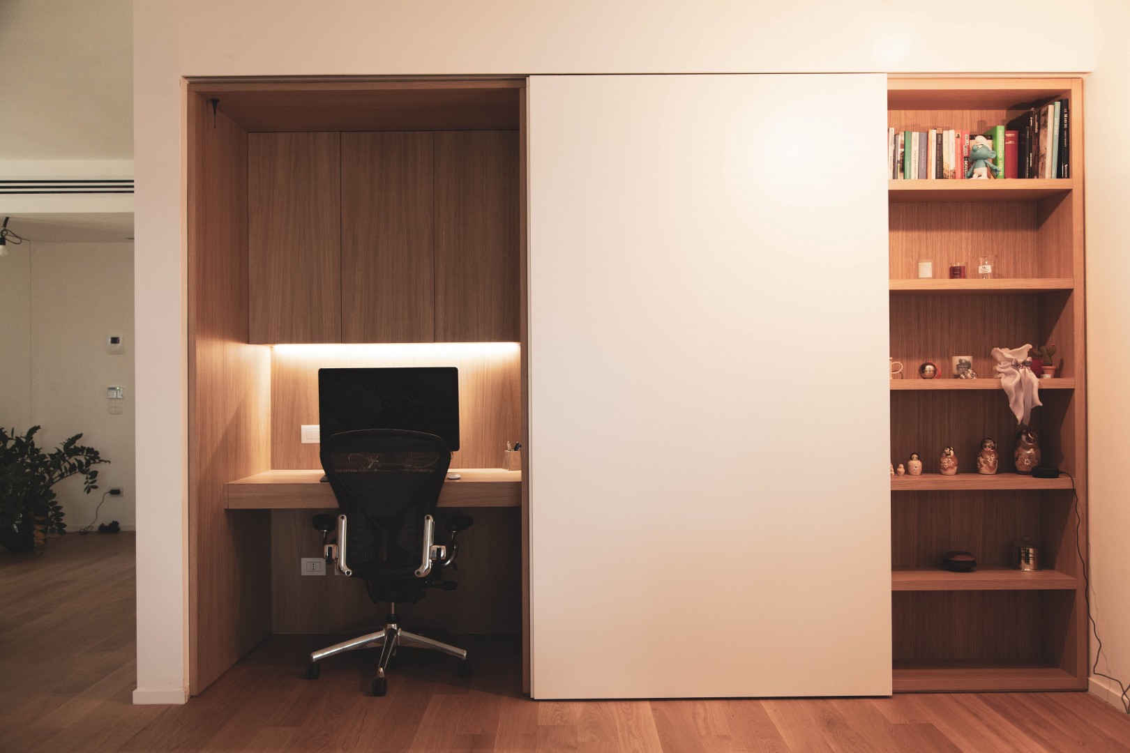 Arredamento su misura realizzato da Profili - Falegnameria & Design. Libreria e zona ufficio con scrivania realizzati in legno rovere. con anta scorrevole laccata.